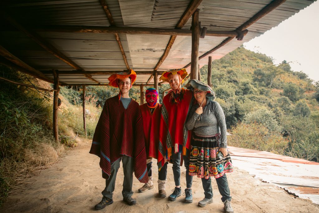 A group of tourists wearing traditional Andean attire, with mountains in the background, on the Inca Jungle Trail to Machu Picchu