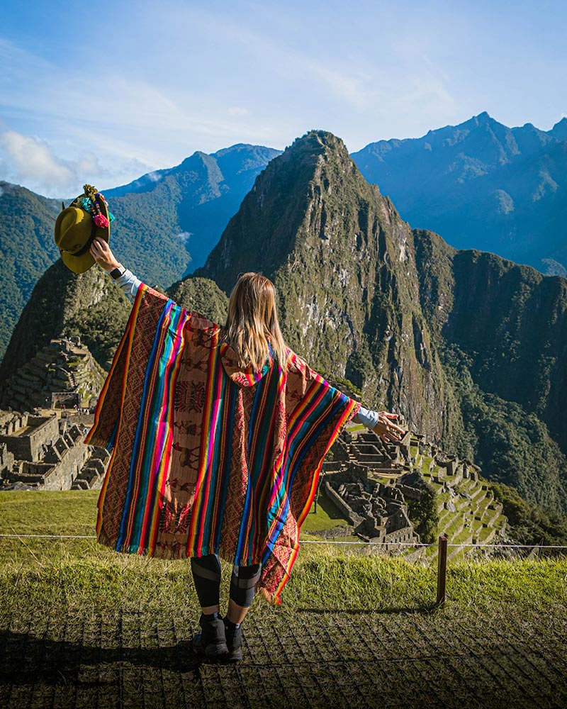 Tourist standing in front of Machu Picchu with open arms